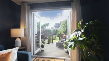 A room with a view of a deck, a sofa, a lamp, and a large potted plant.