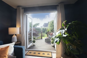 A room with a view of a deck, a sofa, a lamp, and a large potted plant.