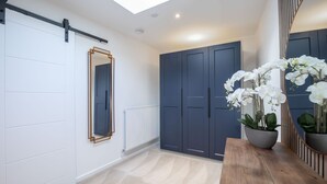 A modern interior with a sliding door, a mirror, a potted orchid, and a wooden table. - Luxurious 1 Bed Detached Home with Gated Parking (Cheltenham)
