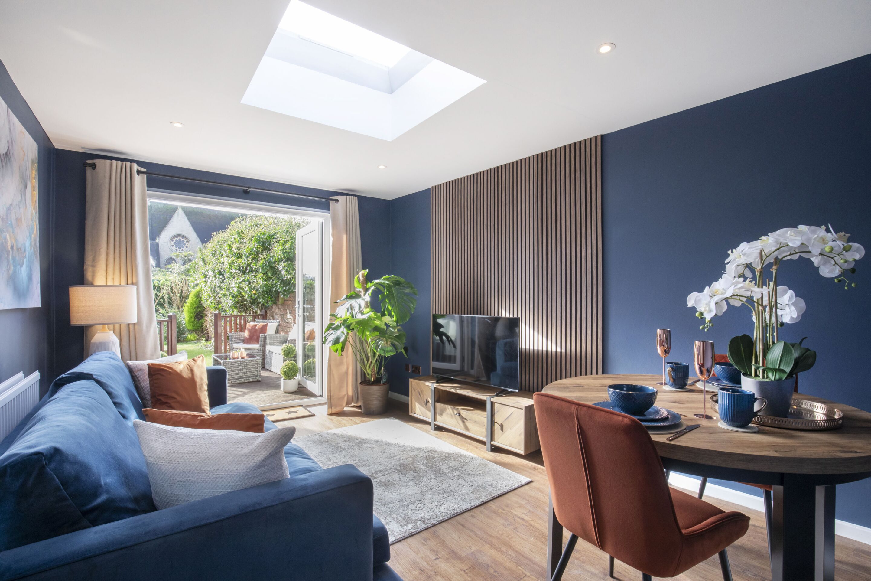 A modern living room with a sofa, TV, and dining area.