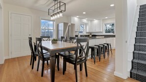 Una cocina moderna con armarios blancos, una mesa de comedor de madera y sillas negras.