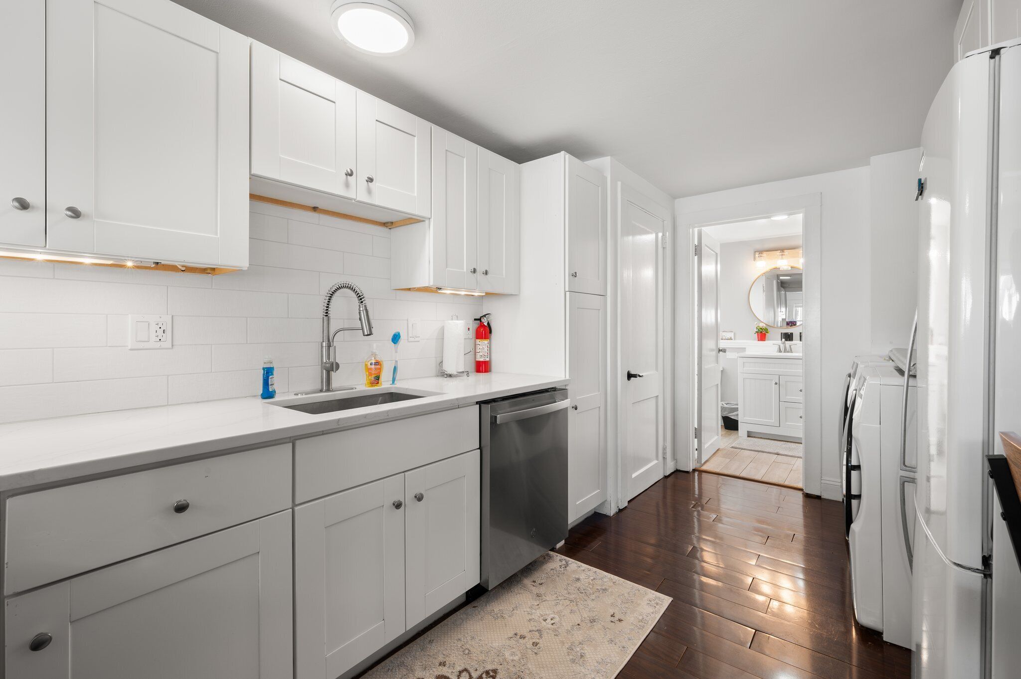 A modern kitchen with white cabinets, a stainless steel dishwasher, and a built-in oven.