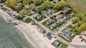 An aerial view of a coastal residential area with houses, a beach, and a road. - Beach Cottage, private beach and pass (East Lyme)