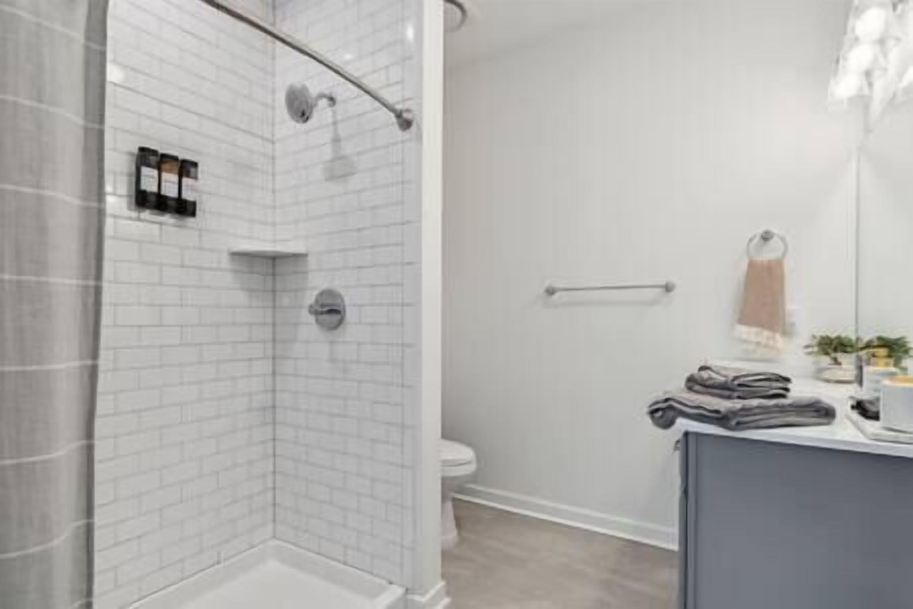 A modern bathroom with a shower, toilet, and a towel rack.