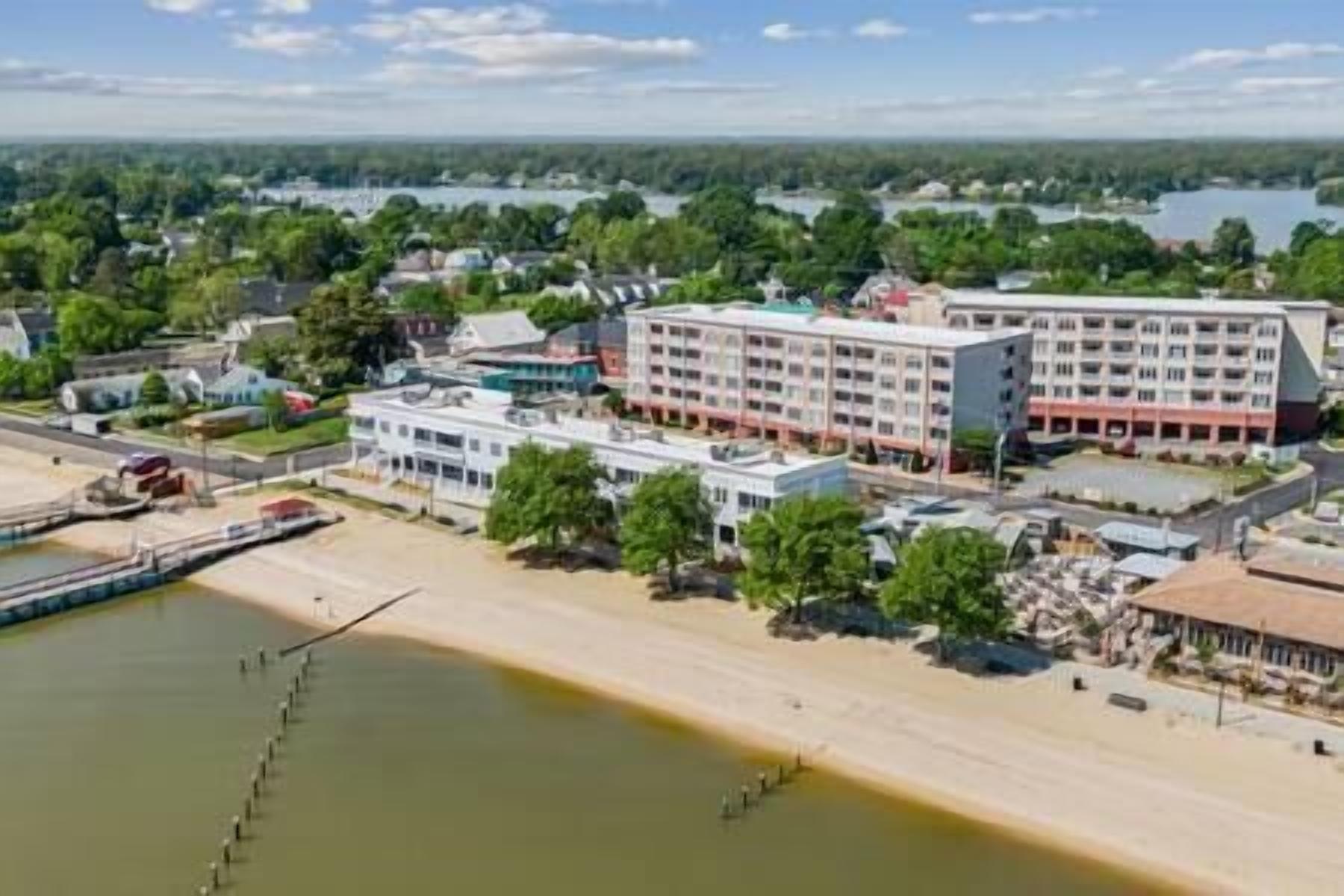 Een kusthotel met meerdere gebouwen, een strand en een meer op de achtergrond.