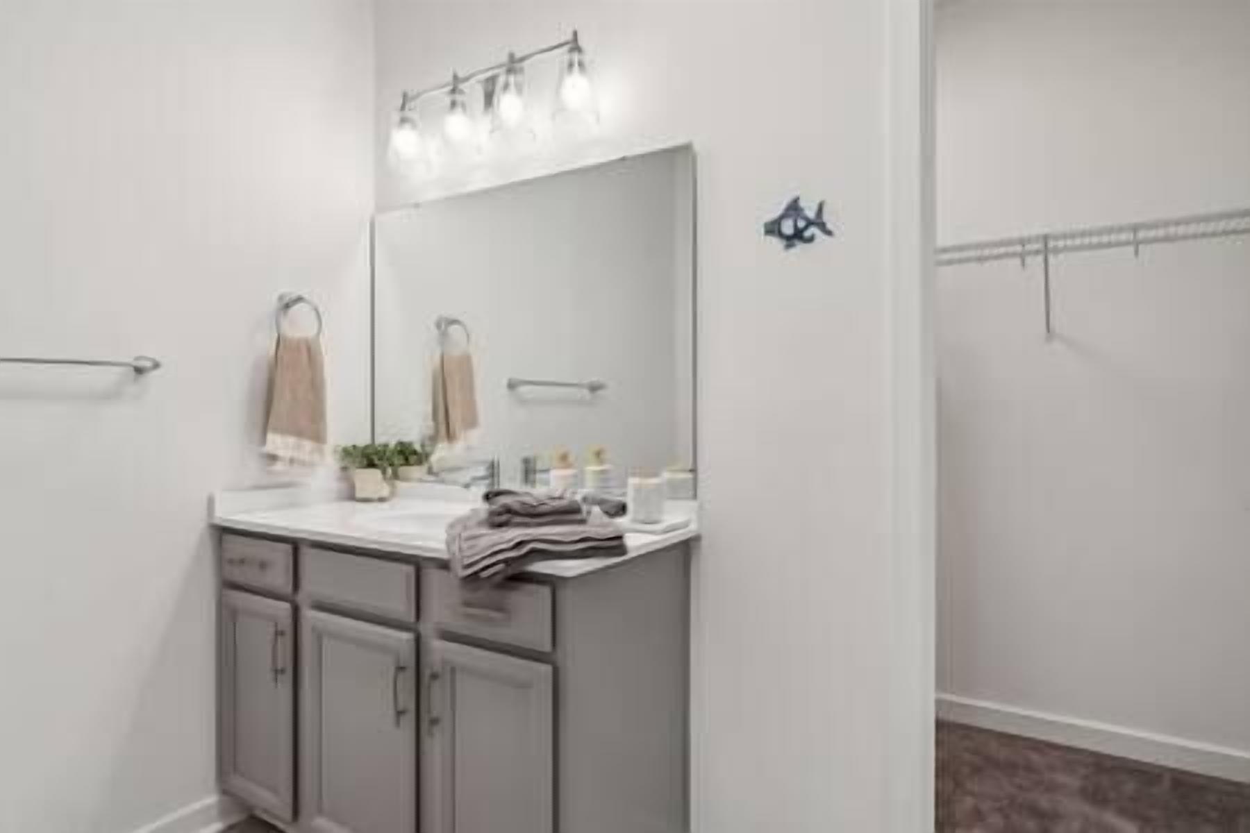 Un baño con un espejo grande, un lavabo y un perchero para toallas.