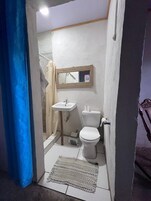 Un baño pequeño y funcional con un lavamanos blanco, un inodoro y un espejo sobre el lavamanos.