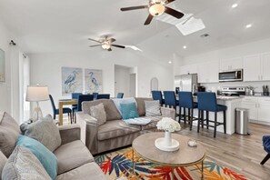 A modern living room with a sofa, coffee table, and ceiling fans.