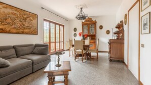 Un soggiorno con divano, tavolino, tavolo da pranzo con sedie, lampadario e credenza decorata.
