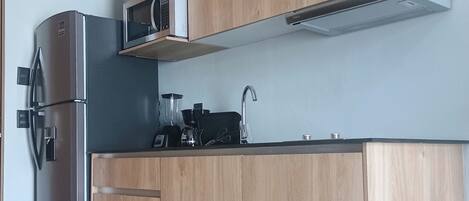 Una cocina moderna con armarios de madera, un refrigerador de acero inoxidable y un microondas.
