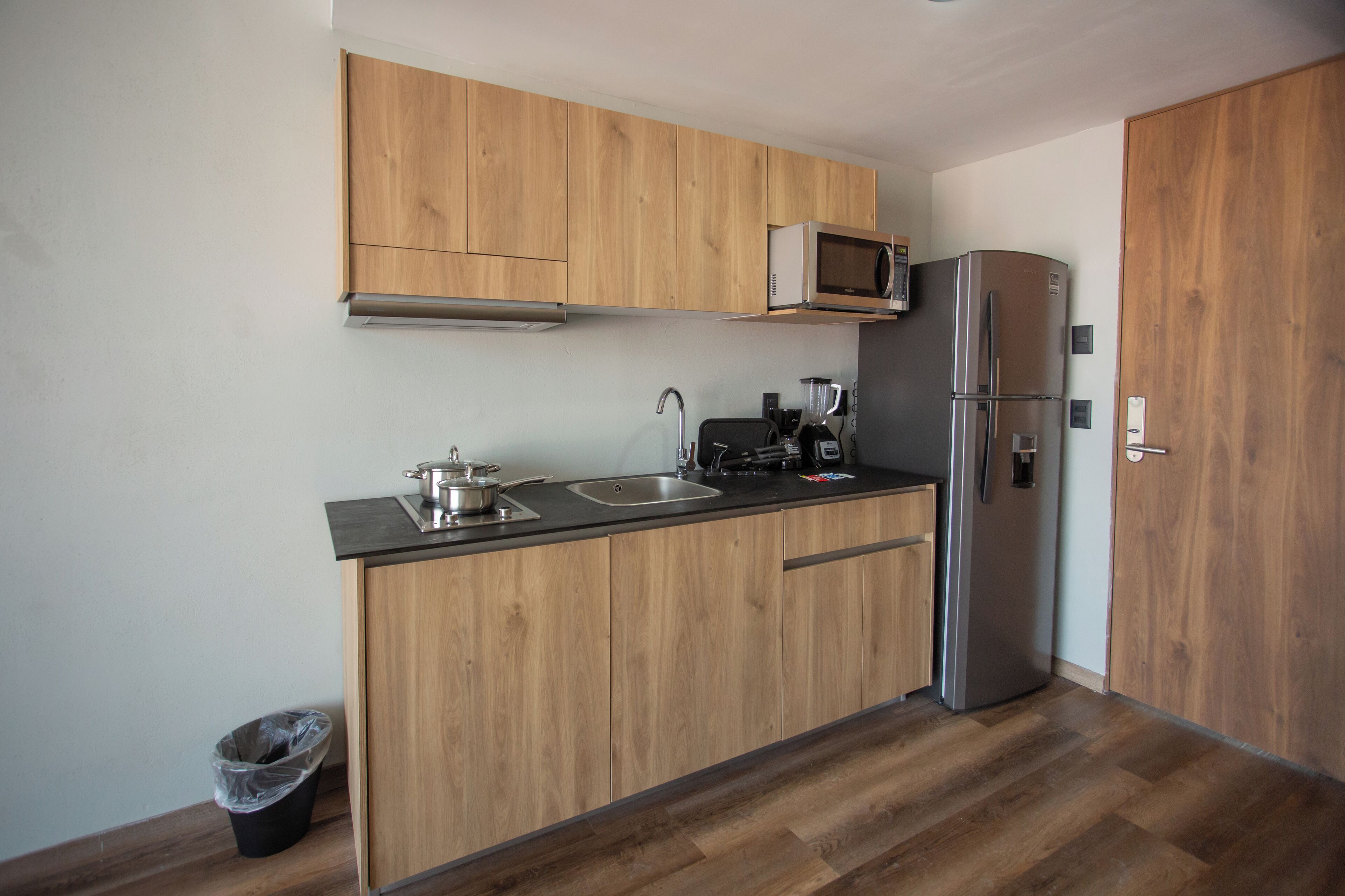 Una cocina moderna con armarios de madera, un refrigerador de acero inoxidable, un microondas y un lavabo.