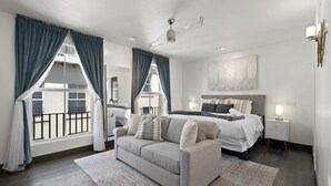 Een moderne slaapkamer met een groot bed, een bank en uitzicht op een balkon.