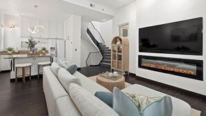 Een moderne woonkamer met een grote televisie, een open haard en een trap naar een hoger gelegen verdieping.