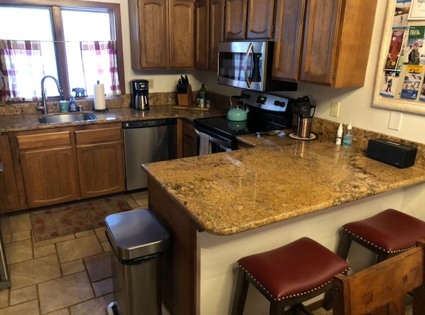A kitchen with granite countertops, wooden cabinets, a stainless steel dishwasher, and a built-in oven. - Cozy, Clean & Conveniently Located Townhome near Eagle Lodge (Mammoth Lakes)