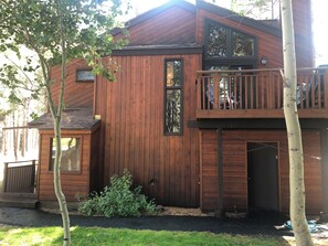 A two-story wooden cabin with a balcony on the upper floor, a front door, and a small porch area. - Cozy, Clean & Conveniently Located Townhome near Eagle Lodge (Mammoth Lakes)