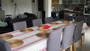 Un coin repas avec une longue table, agrémentée de sets de table en fibres tressées, de chaises et d’une serviette rouge.