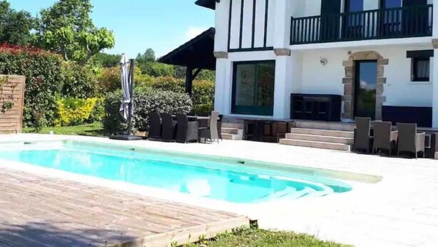 Une maison à deux étages dotée d’une piscine, d’un espace extérieur aménagé et d’un patio couvert.