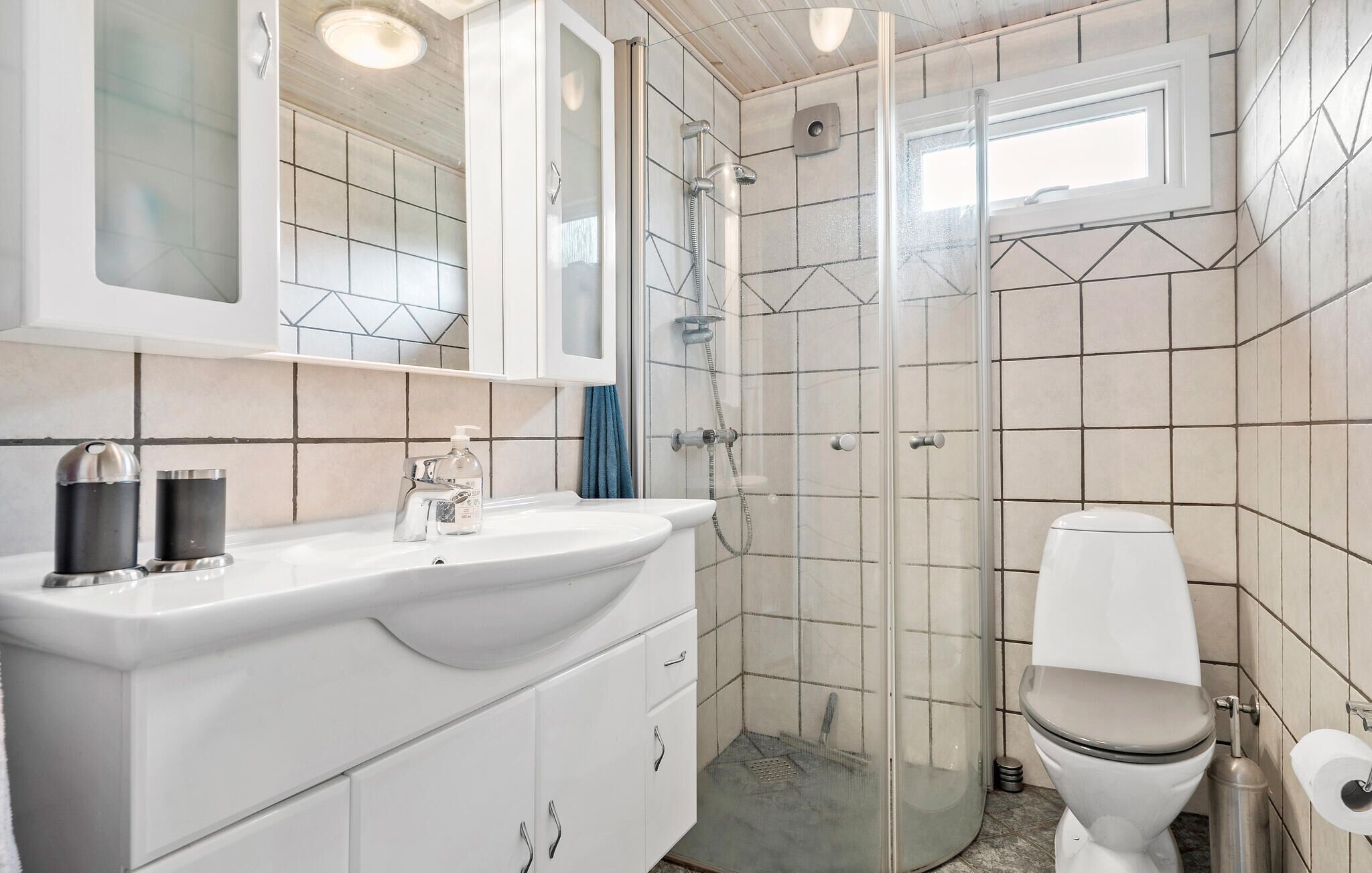 A bathroom with a white sink, mirror, and toilet.