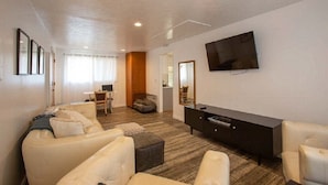 Una sala de estar moderna con un juego de sofá, un televisor de pantalla plana y un mueble de madera oscura.