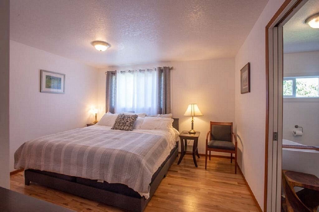 Une chambre à coucher avec un lit, des tables de chevet, une chaise et une fenêtre avec des rideaux.