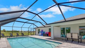 Una piscina exterior cubierta con zona de terraza, sillas de descanso y vistas del paisaje circundante.