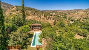 A pool area with a wooden deck, surrounded by lush greenery and a mountainous backdrop. - 5 bedroom amazing home in Restabal (Restabal)