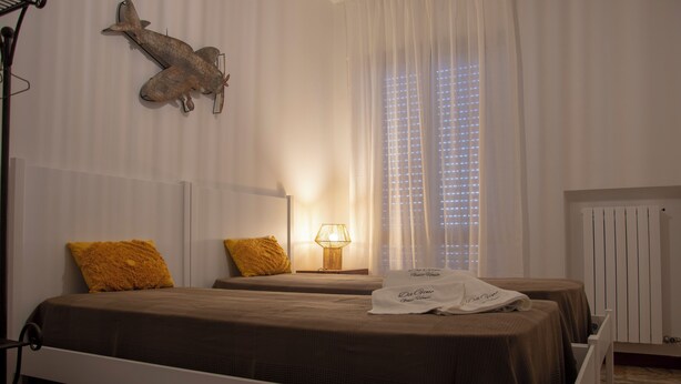 Et hotelværelse med to senge, en lampe, et vindue med rullegardiner og en dyredekoration på væggen.