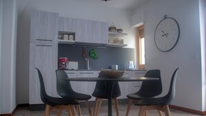 Et moderne køkken med hvide skabe, et sort spisebord og tre sorte stole.