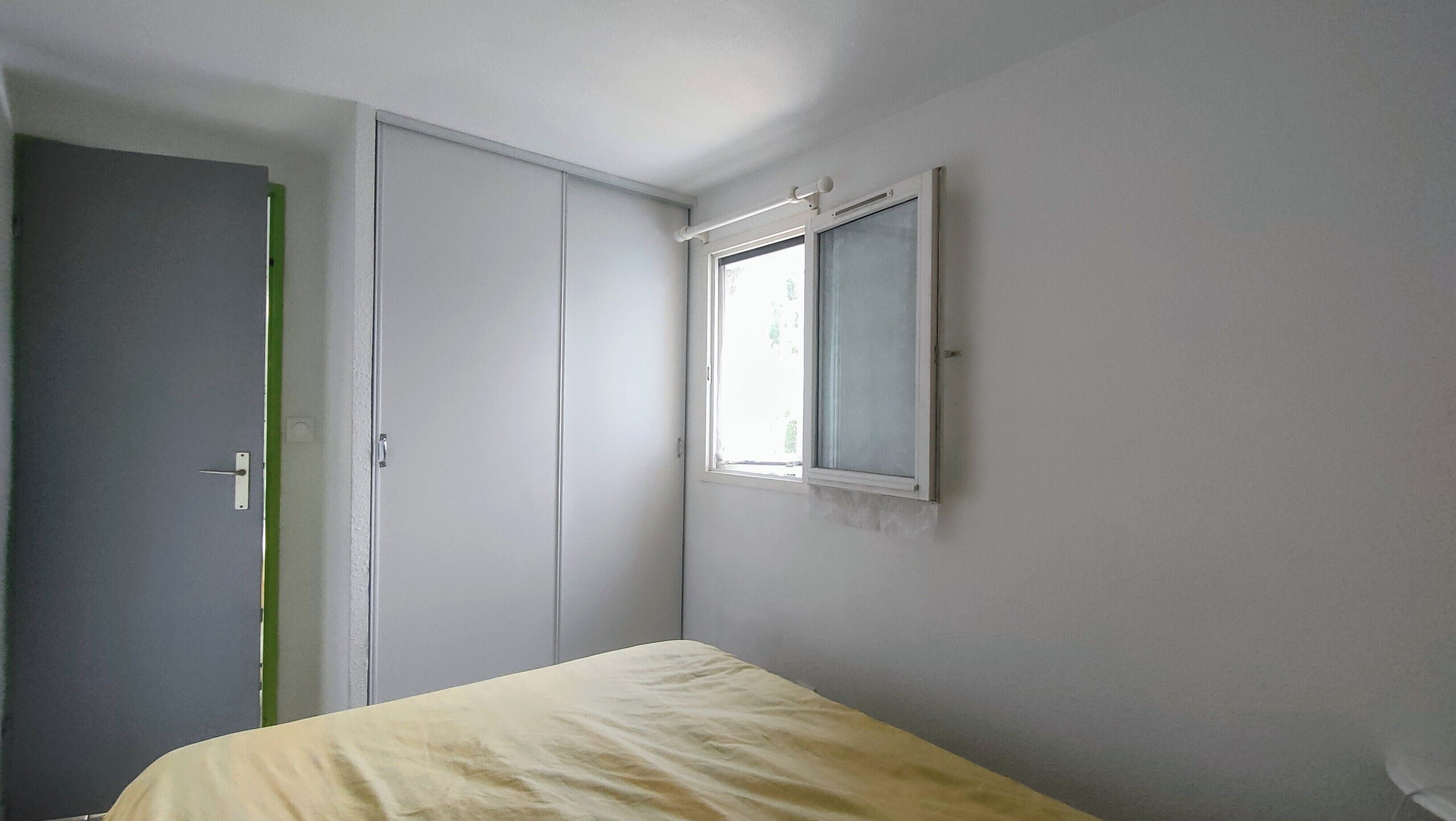 A bedroom with a bed, a wardrobe, and a window.