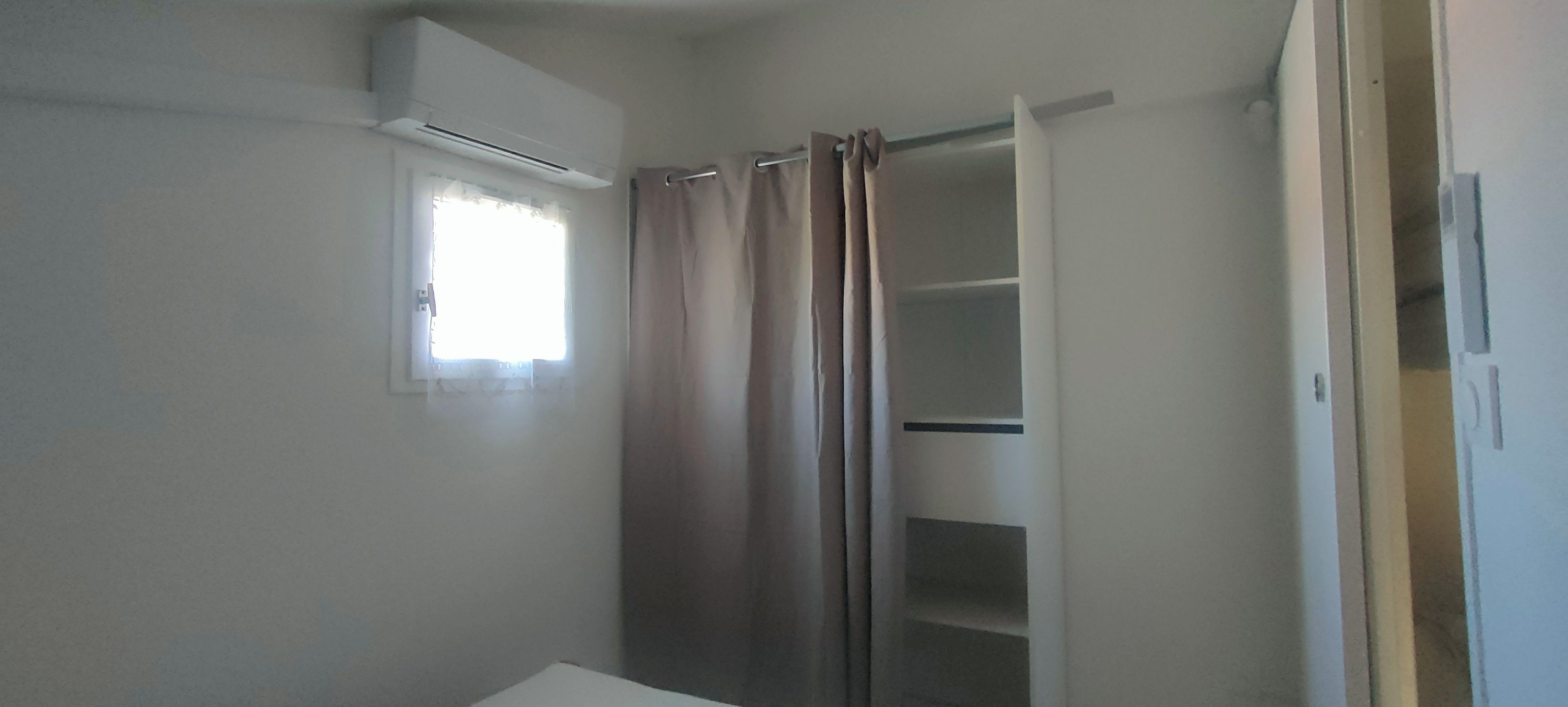 A bathroom with a shower curtain, a window with a curtain, and a white door.