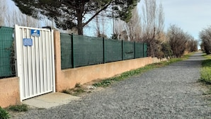 Ein Kiesweg führt zu einem verschlossenen Eingang mit einem blauen Schild.