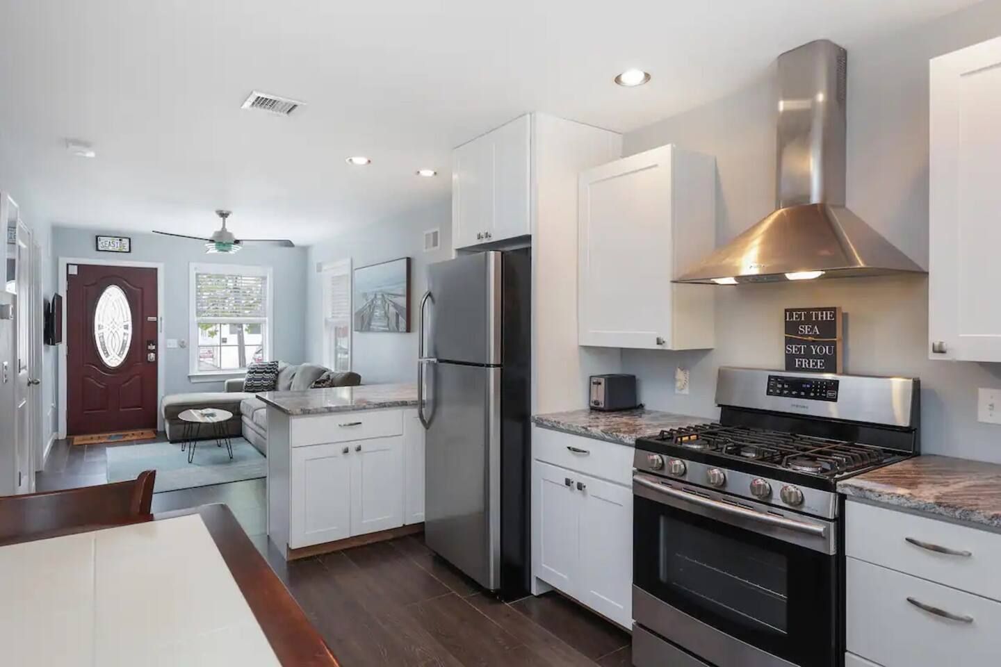 A modern kitchen with stainless steel appliances, white cabinetry, and a built-in oven.