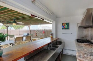 Una cocina con barra de madera, lavamanos de acero inoxidable y estufa a gas.