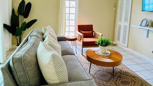 Een woonkamer met een bank, fauteuil en een ronde salontafel met een plant.