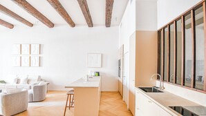 A modern kitchen with a large window, wooden beams, and a herringbone floor. - Le Marcel - Appart standing 3 ch avec clim (Marseille)