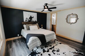 A bedroom with a bed, a ceiling fan, a cowhide rug, and a wall-mounted mirror. - Minutes to I-65! Clean Modern Home: Trail ride, Stargaze, Firepit &more (Elizabethtown)