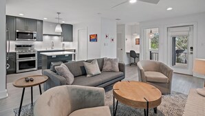 A modern kitchen with built-in appliances, a grey sofa, and a round wooden table. - Waterfront/Walk to Public Beach! (Seagrove Beach)
