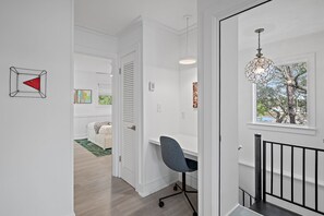 Una habitación moderna y luminosa con un escritorio, una silla y una lámpara colgante.