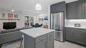 A modern kitchen with grey cabinets, a stainless steel refrigerator, and a white island. - Waterfront/Walk to Public Beach! (Seagrove Beach)
