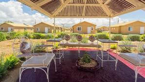 Un espace extérieur abrité, aménagé avec des chaises et des tables en métal, et entouré d’immeubles aux façades uniformes.