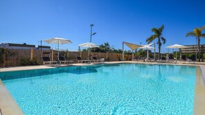 A clear blue pool with lounge chairs and umbrellas, surrounded by palm trees and a wooden fence. - Stunning home in Marza (Marza)