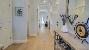 Un couloir aux murs blancs, doté d’un plancher en bois et agrémenté d’un banc orné d’objets décoratifs.