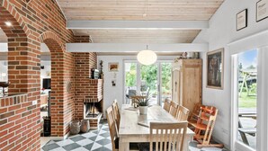 Een eetruimte met een metselwerk open haard, een houten eettafel en stoelen.