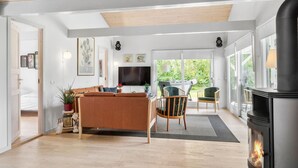 Een moderne woonkamer met een bank, stoelen, een open haard en een televisie.