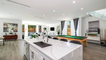 A modern kitchen with a central island, built-in appliances, and a pool table.