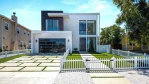 Une maison moderne à deux étages, avec une façade blanche, de grandes fenêtres et une pelouse bien entretenue.