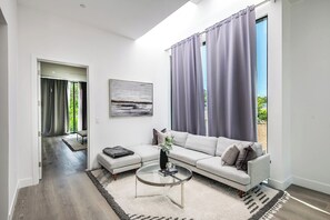 Un salon moderne avec un canapé, une table basse et un tableau accroché au mur.