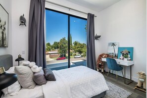 Un dormitorio con cama, escritorio y vistas al exterior.