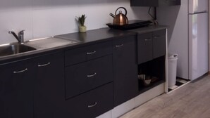 Una cocina moderna con armarios negros, un lavamanos de acero inoxidable, un microondas y un refrigerador blanco.