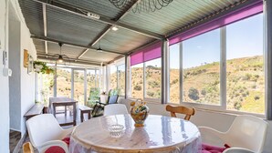 A dining area with a round table, chairs, and a view of a hilly landscape through large windows. - Lovely home in Canillas de Albaidas (Canillas de Albaidas)